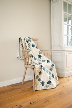 a chair with a blanket on top of it in front of a wall and window