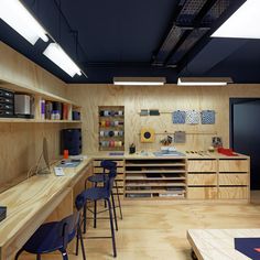 a room with wooden shelves and blue stools in front of the counter, along with several other items