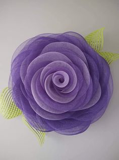 a large purple flower with green leaves on it's center and the petals are made from mesh