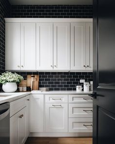 a kitchen with white cabinets and black tile backsplash