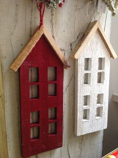 two red and white birdhouses hanging on a wall next to each other with flowers in them