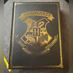 a hogwarts book sitting on top of a gray couch next to a yellow ribbon