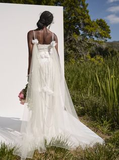 a woman in a wedding dress is standing outside