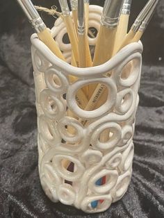 a close up of a cup with pens and pencils in it