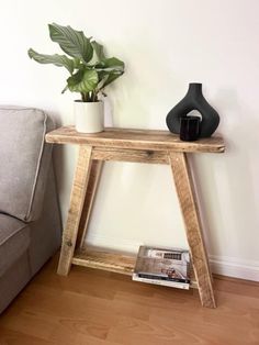 a wooden table sitting next to a couch with a plant on it and a magazine