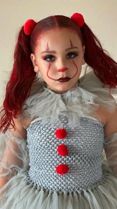 a doll with red hair wearing a dress and clown make up on it's face