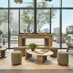 a living room filled with lots of furniture next to large glass windows on top of a building