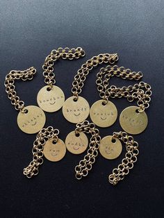 a bunch of gold tags that are sitting on a black surface with words written on them