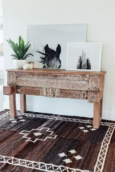 a wooden table with pictures on top of it and a rug in front of it