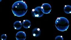 soap bubbles floating in the air on a black background with blue light reflecting off them