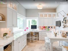 a kitchen with lots of white cabinets and counter top space in front of a window