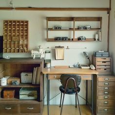 an old fashioned desk with lots of drawers and shelves on the wall, along with a chair in front of it