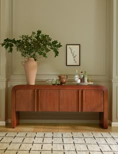 there is a potted plant on top of a wooden table in the corner of this room