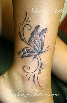 a tattoo on the side of a woman's leg with a flower and swirls