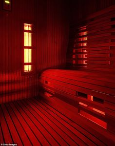 a sauna room with red light coming through the window and wood flooring on the walls