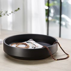 a round black tray with beads on it and a white vase in the back ground