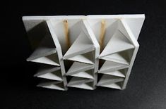 three pieces of white paper stacked on top of each other in the shape of pyramids