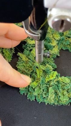 someone is using a drill to make a wreath out of fake moss and other greenery