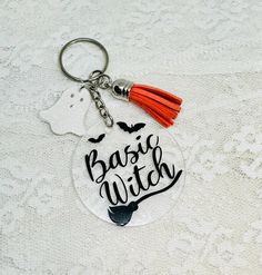 a keychain with the words basic witch written on it and an orange tassel