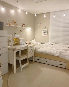 a bedroom with a bed, desk and dressers in the corner is lit by lights