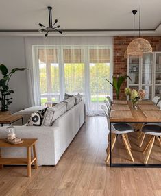 a living room filled with furniture and a dining table in front of a brick wall