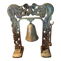 an ornate metal bell with two dragon heads on it's sides and a large bell in the middle