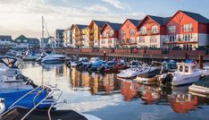 many boats are docked in the water near some red and white houses with blue trim