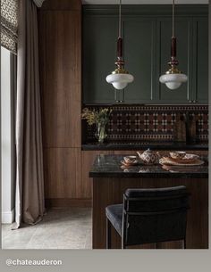 a kitchen with two lights hanging over the stove top and countertop, along with a bar stool