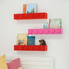 two lego shelves on the wall above a bed with a teddy bear and bookshelf