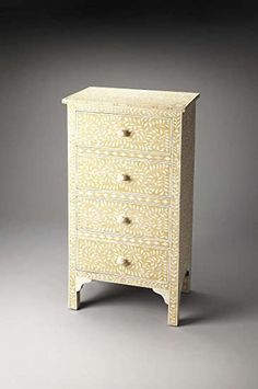 a white and yellow chest of drawers with two drawers on one side and an ornate design on the other