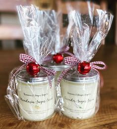 two small jars filled with candles on top of a wooden table and wrapped in plastic