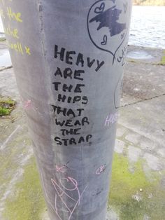 graffiti on the side of a pole near water