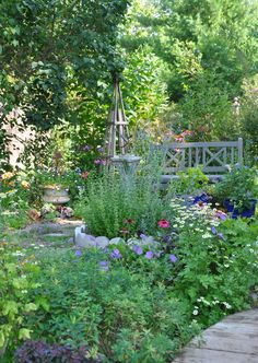 a garden filled with lots of different types of flowers and plants next to a wooden walkway