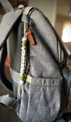 a backpack with a name tag hanging from it's front pocket and zippers