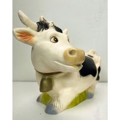 a ceramic cow figurine sitting on top of a table next to a white wall