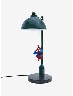 a lamp with a spiderman hanging from it's side