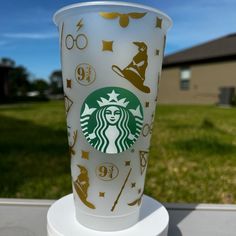 the starbucks cup is decorated with harry potter symbols and other things in gold on white