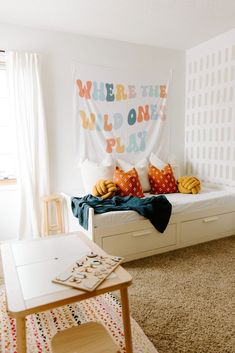 a room with a bed, table and rug on the floor in front of it