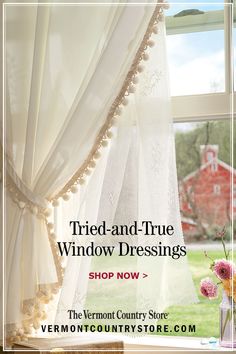 a window with white curtains and pink flowers in vase next to the window sill