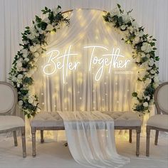 a white wedding arch decorated with flowers and greenery