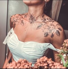 a woman with tattoos on her chest and shoulder