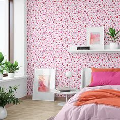 a bedroom decorated in pink and orange with floral wallpaper, potted plants and bedding