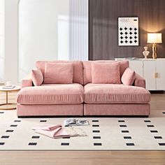 a pink couch sitting on top of a wooden floor next to a white and black checkered rug