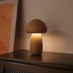 a mushroom shaped lamp sitting on top of a wooden table next to a framed painting