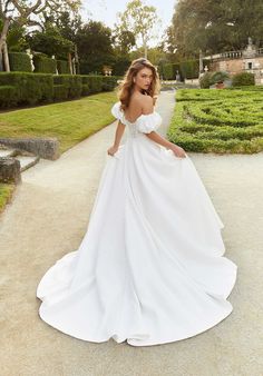 a woman in a white wedding dress standing on a path