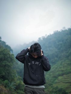 a man standing in front of a lush green hillside