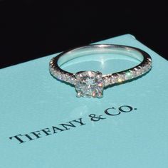 a diamond ring sitting on top of a blue box with the words tiffany & co written below it