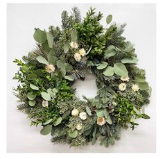 a green wreath with white flowers and greenery