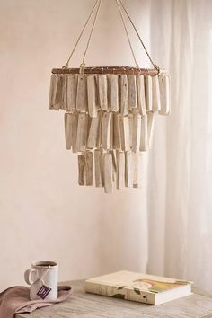 a chandelier hanging from the ceiling over a table next to a book and cup