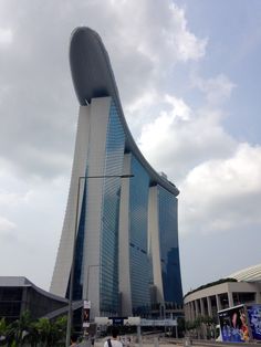 people are walking around in front of a tall building with a curved design on the side